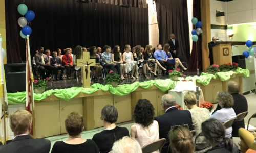 group of students sitting on stage during ceremony