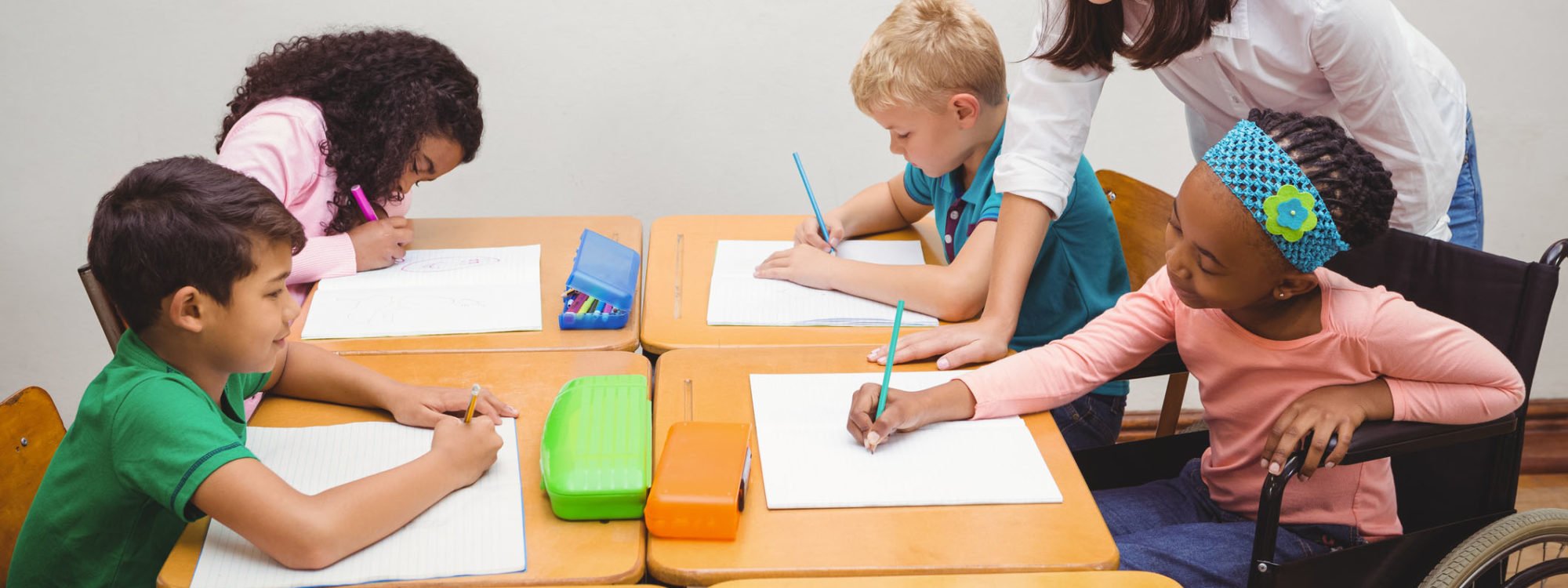 Happy teacher helping her students at the elementary school