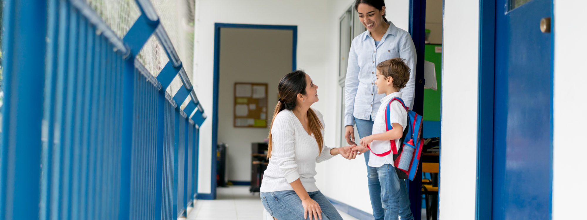 Portrait of a mother picking up her kid from school and talking to the teacher while looking happy - education concepts