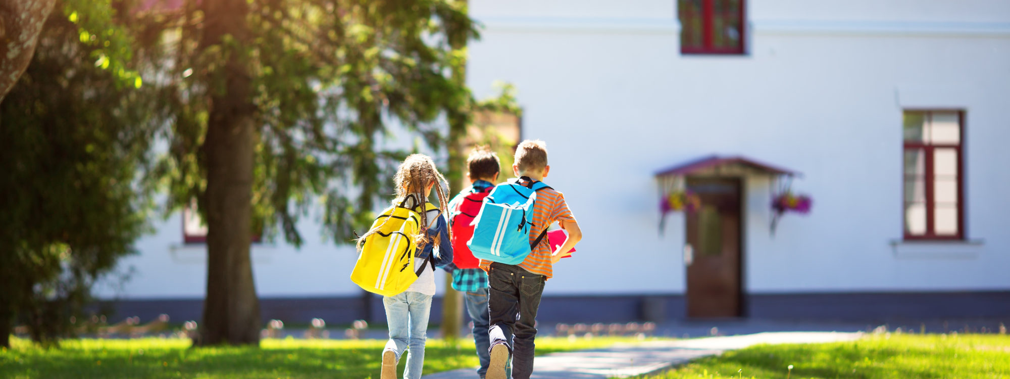Children with rucksacks running in the park near school. Pupils with books and backpacks outdoors