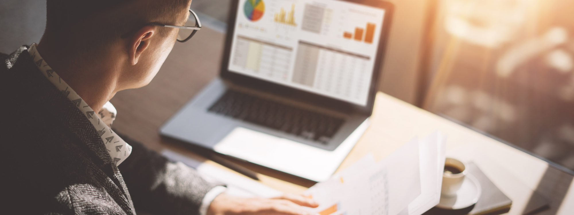 man working at laptop with desk and reports
