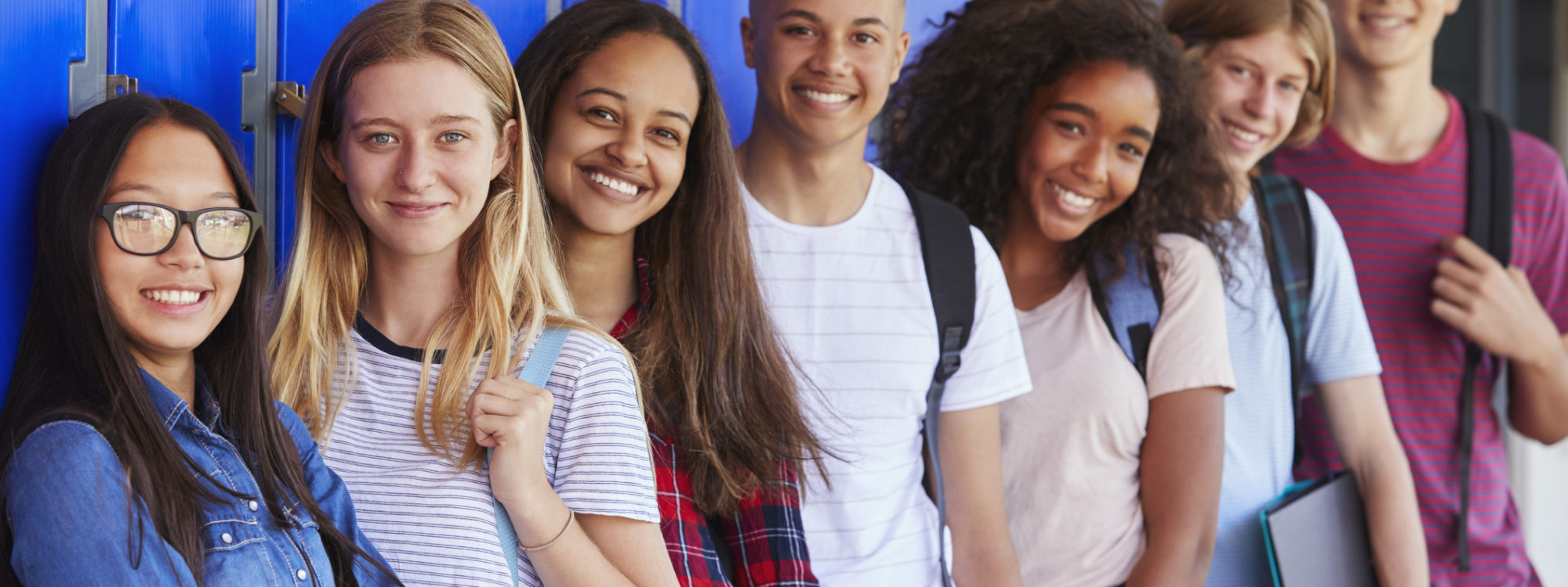 Teenage school kids smiling to camera in school corridor