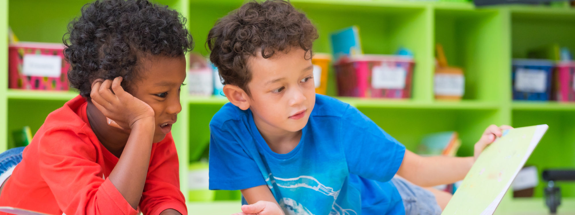 Two boy kid lay down on floor and reading tale book in preschool library,Kindergarten school education concept.