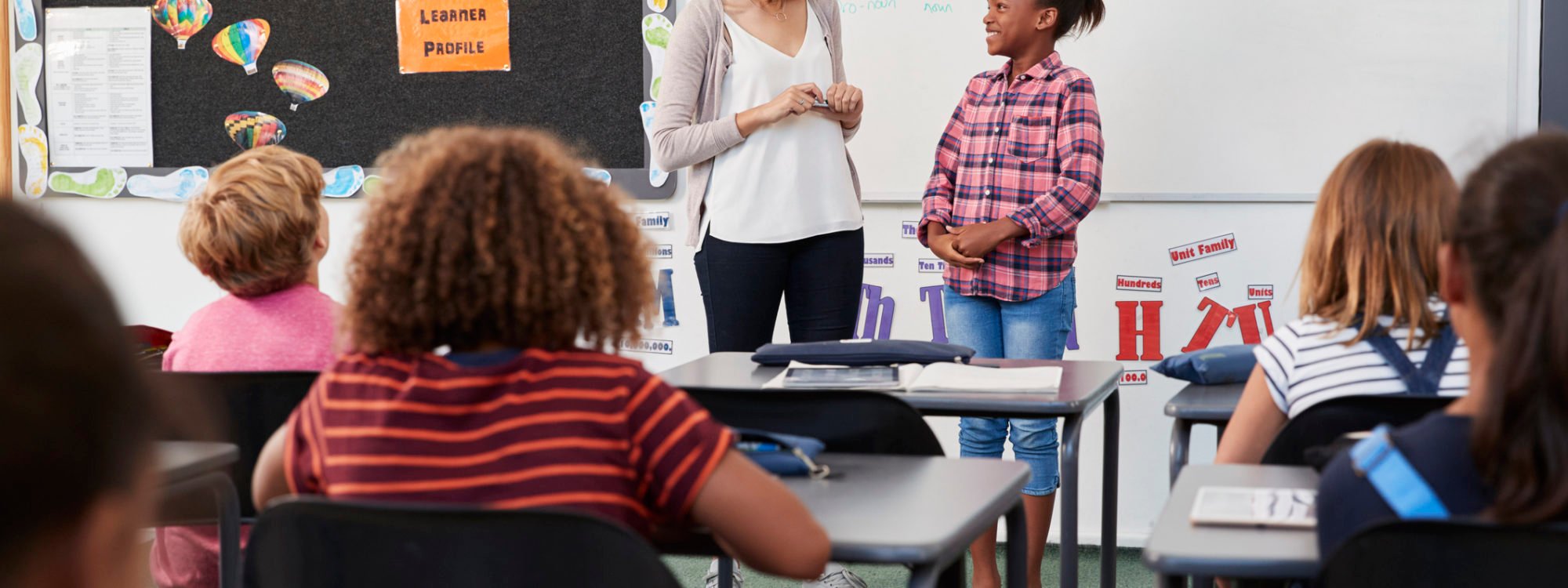 Teacher and pupil stand at front of elementary school class