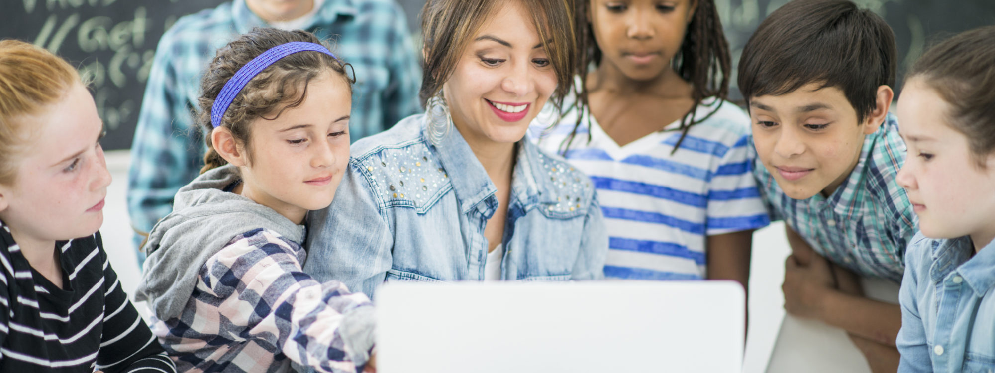 students and teacher using laptop on desk