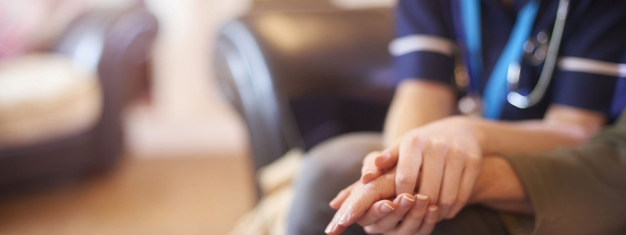 A female nurse consoles a senior patient at home