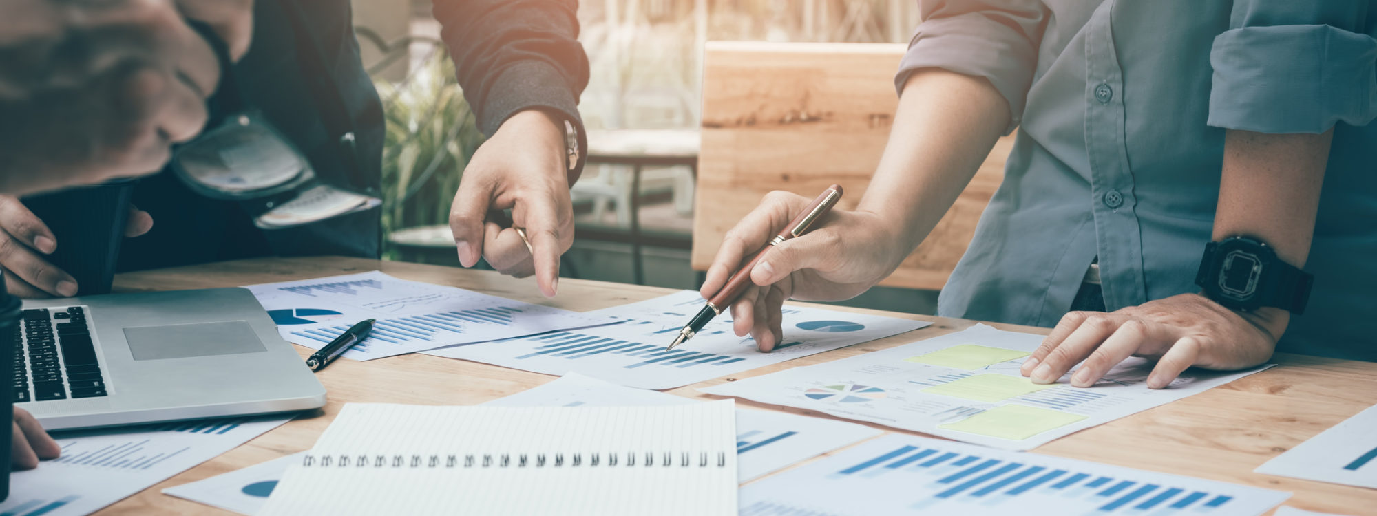 Co-working space office with group start-up analysis to data paper chart on desk.
