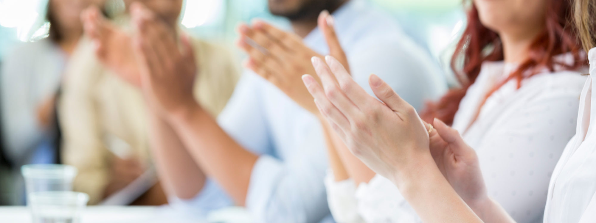 Diverse businesspeople applaud the speaker during a business conference. Focus is on their hands.