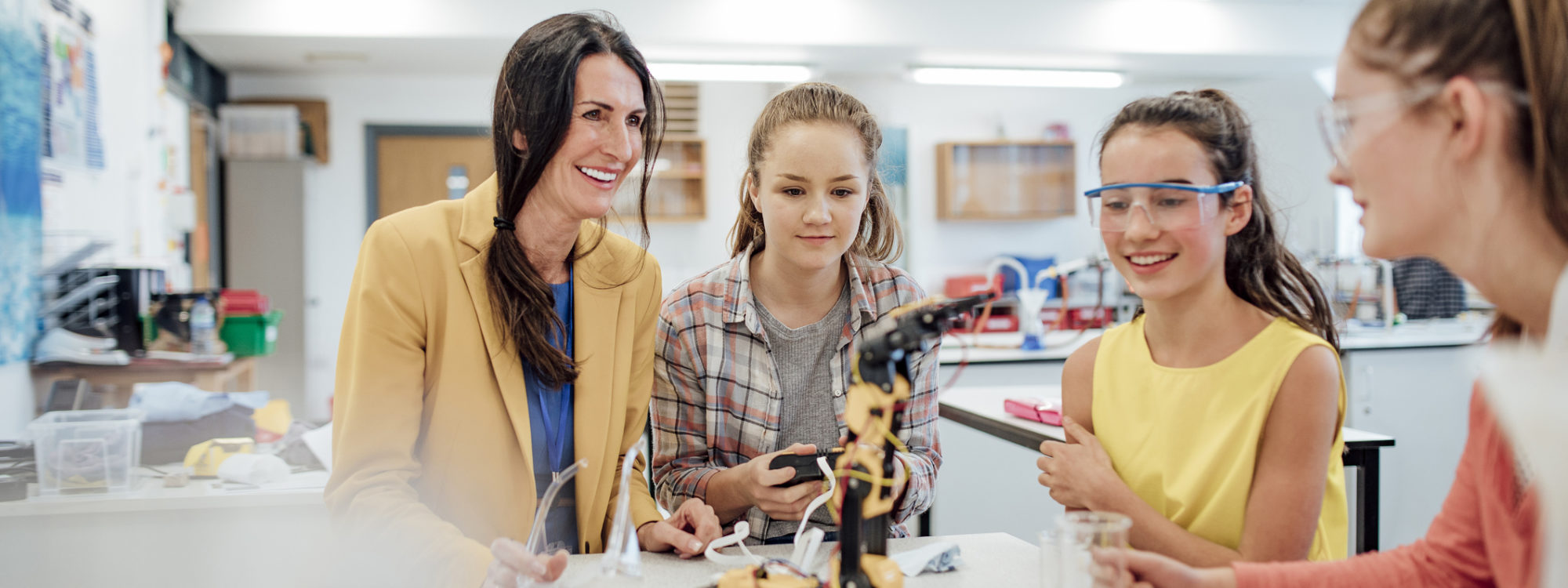 Point of view angle of teenage girls studying robotic arm in school.