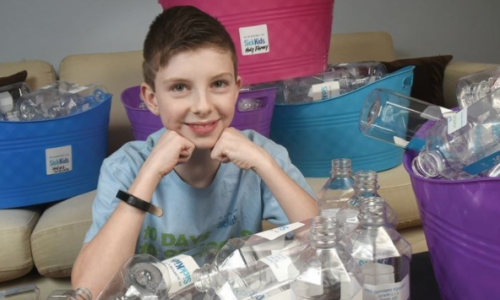 student with plastic water bottles for recycling