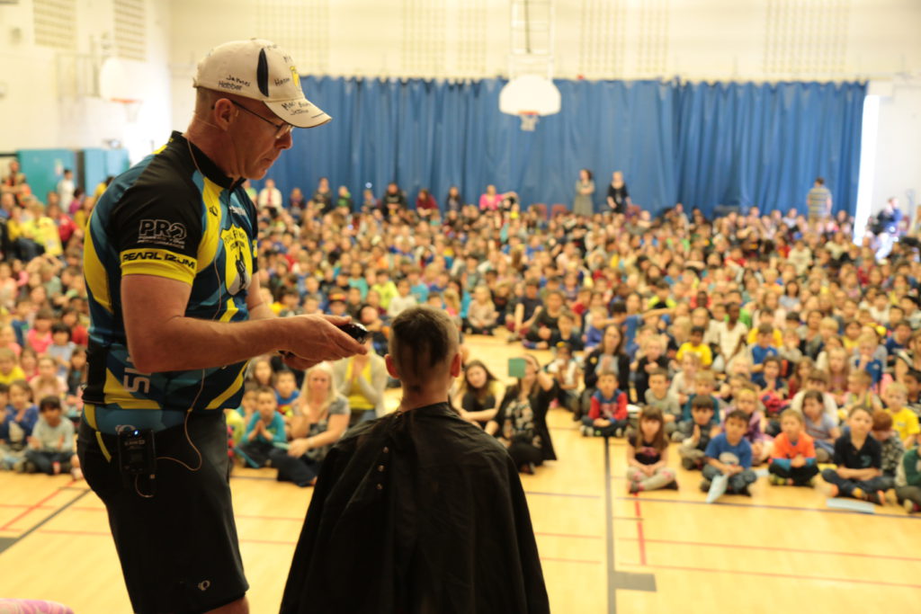 student getting hair cut on stage