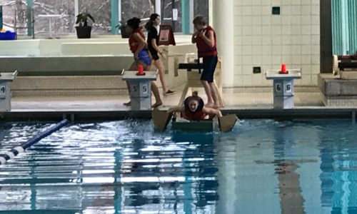 student competing in cardboard boat race