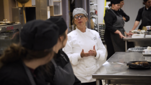 woman instructing students in learning kitchen