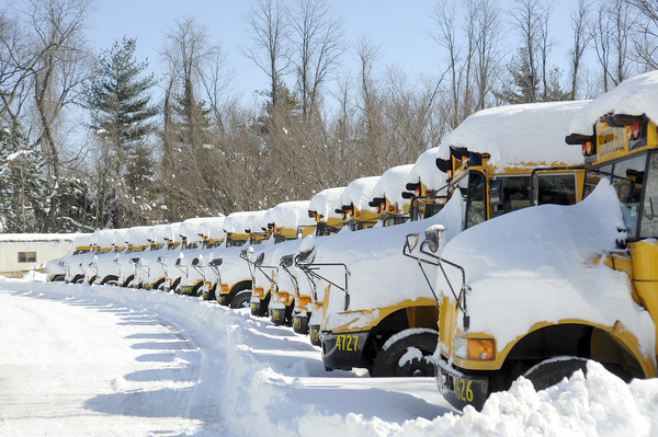 a line of parked busses covered in snow