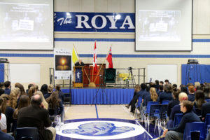man speaking at podium in gymnasium