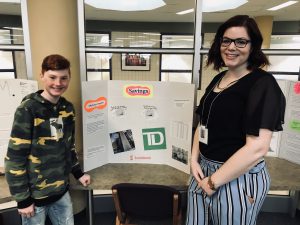 student and teacher standing next to presentation