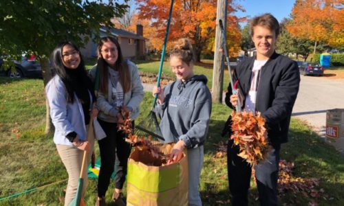 4 students raking up leaves