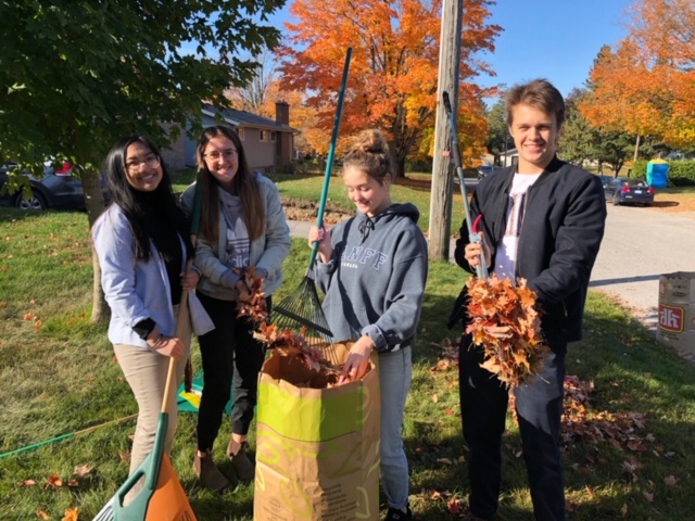 4 students raking up leaves