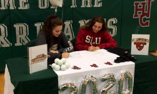 two students sitting at decorated table signing letter