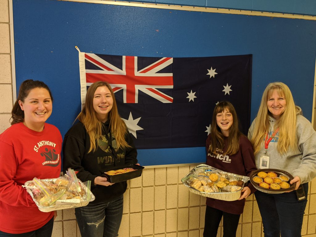 staff and student holding baked goods for sale
