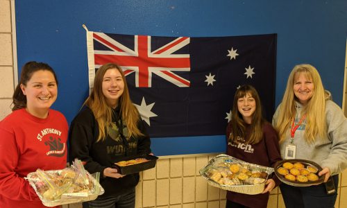 staff and student holding baked goods for sale