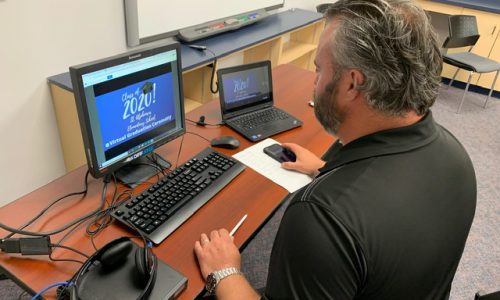 Principal working on a laptop live streams the Board's first ever virtual grad ceremony
