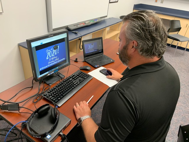 Principal working on a laptop live streams the Board's first ever virtual grad ceremony