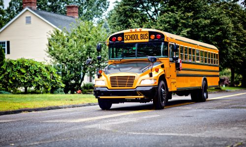 Yellow school bus driving along street