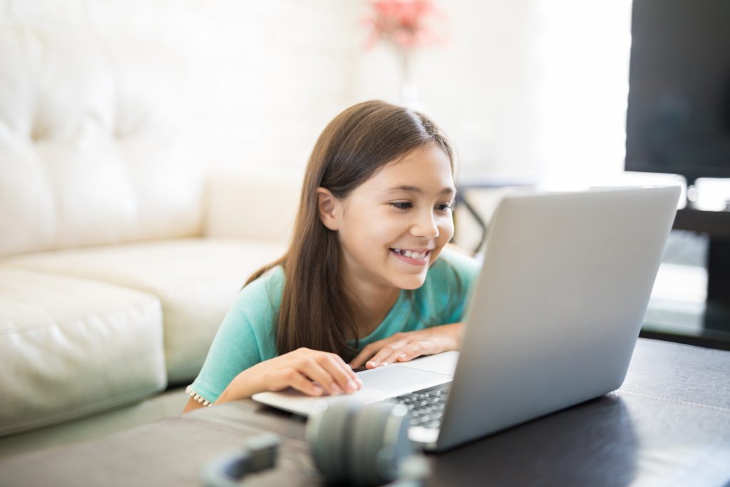 Little student girl with laptop pc at home