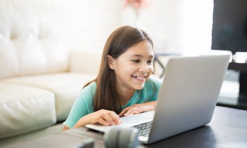 Little student girl with laptop pc at home