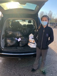 Photo of student in front of car filled with bags.
