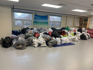 Piles of bags in classroom filled with collected shoes.