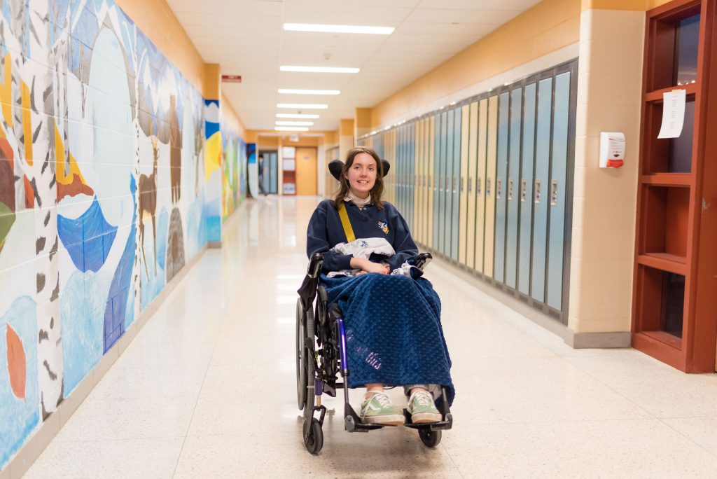 Katie Girard in her wheelchair in St. Stephen hallway.