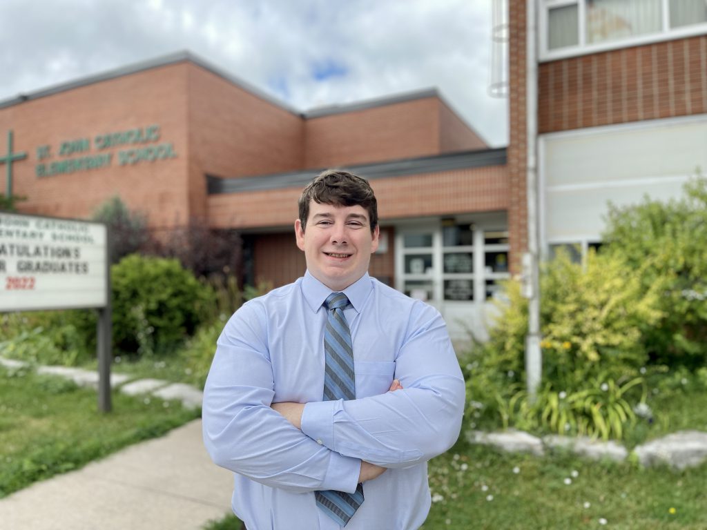 Man standing in front of school with arms crossed