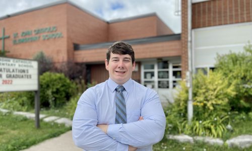 Man standing in front of school with arms crossed