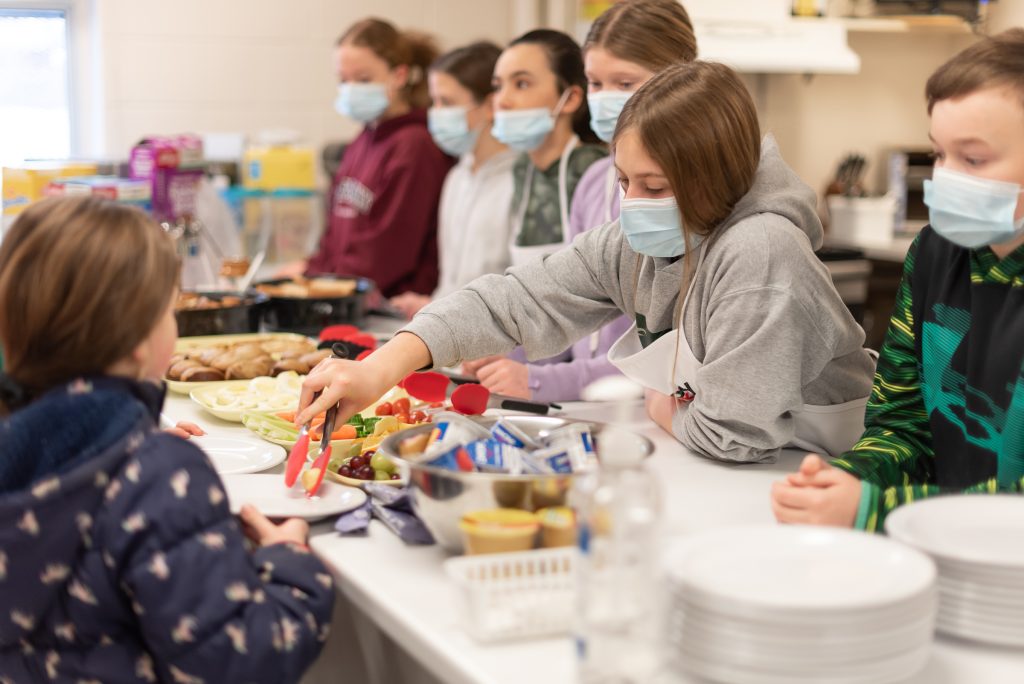 Volunteer feeding students during school based nutrition program