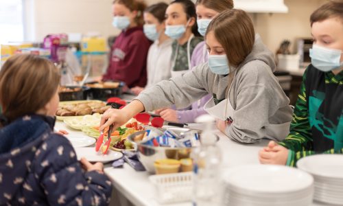 Volunteer feeding students during school based nutrition program