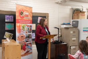 Director Joan Carragher speaking at podium