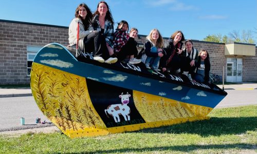 Students sit upon a snow plow that they painted