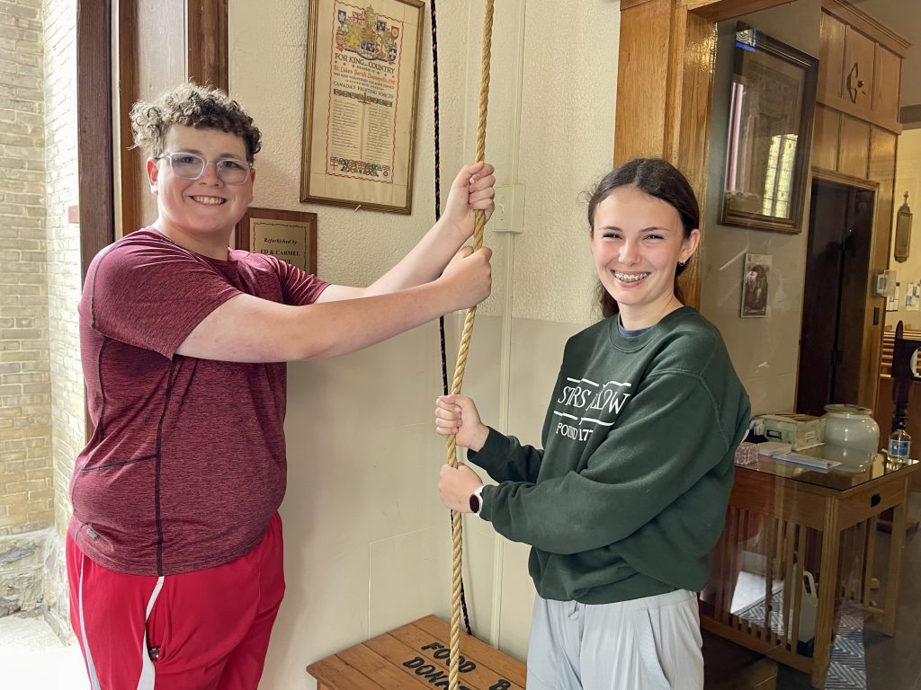 Students hold a bell rope in a church