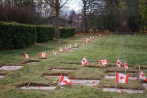 Photo of grave markers with Canadian flags and poppies.