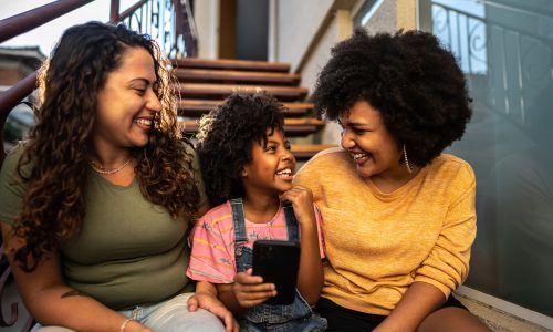 Image of a child with a smart phone enjoying a laugh with two adults