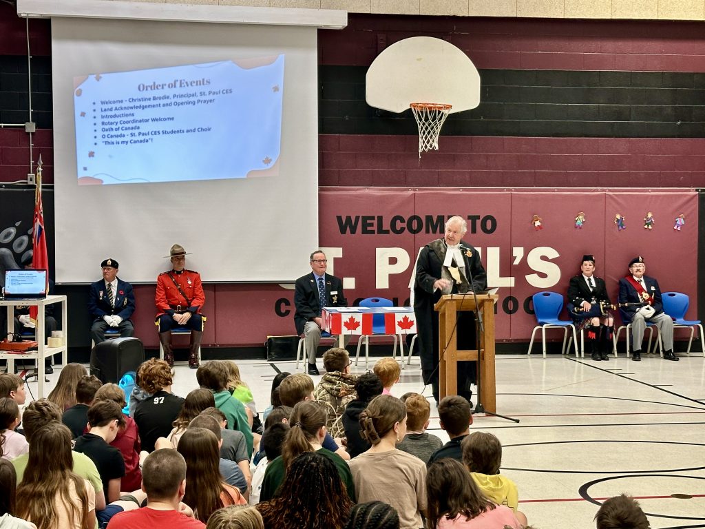 A judge leads a citizenship ceremony at a school gymnasium