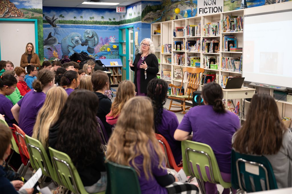 Classroom full of students listening to a presenter at the front of the room.