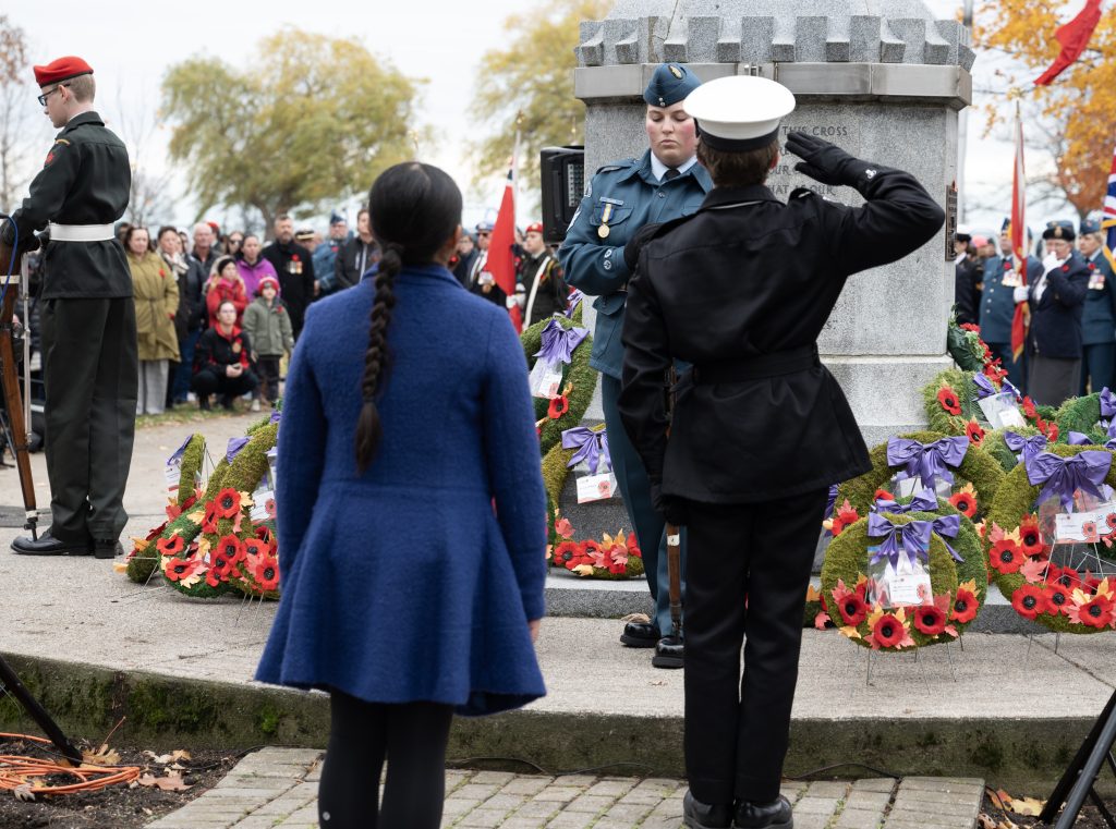 Two students approach the cenotaph with a wreath