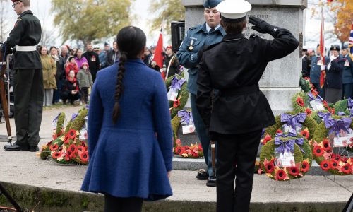 Two students approach the cenotaph with a wreath