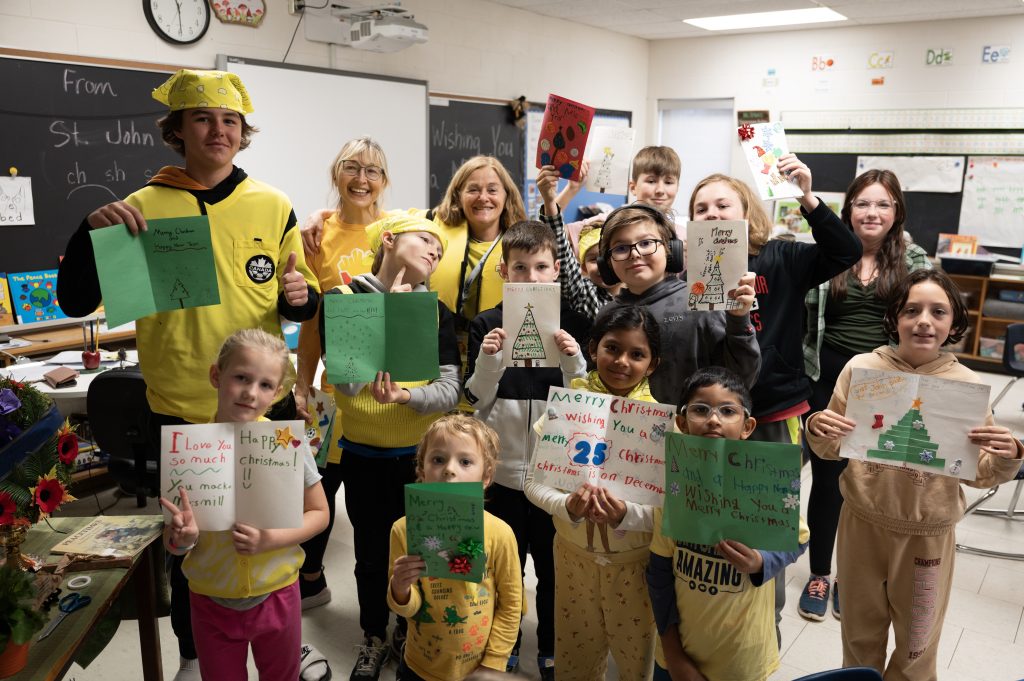 Group of students holding up Christmas cards.