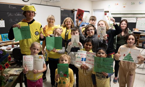 Group of students holding up Christmas cards.