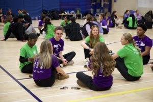 Group of students sitting in a circle in a gymnasium