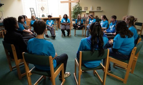 Group of students wearing blue sitting in a circle